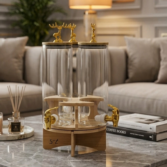 3-in-1 revolving clear glass beverage dispenser with golden taps set on a marble coffee table