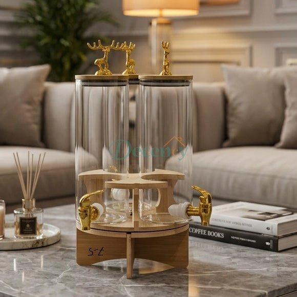 3-in-1 revolving clear glass beverage dispenser with golden taps set on a marble coffee table