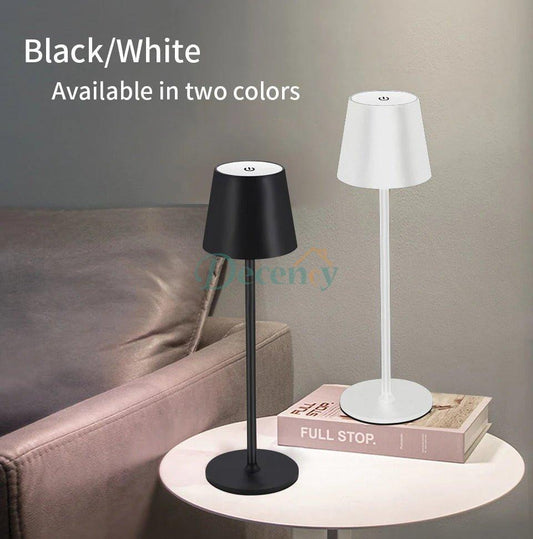 Two table lamps, one black and one white, on a table with a couch in the background.
