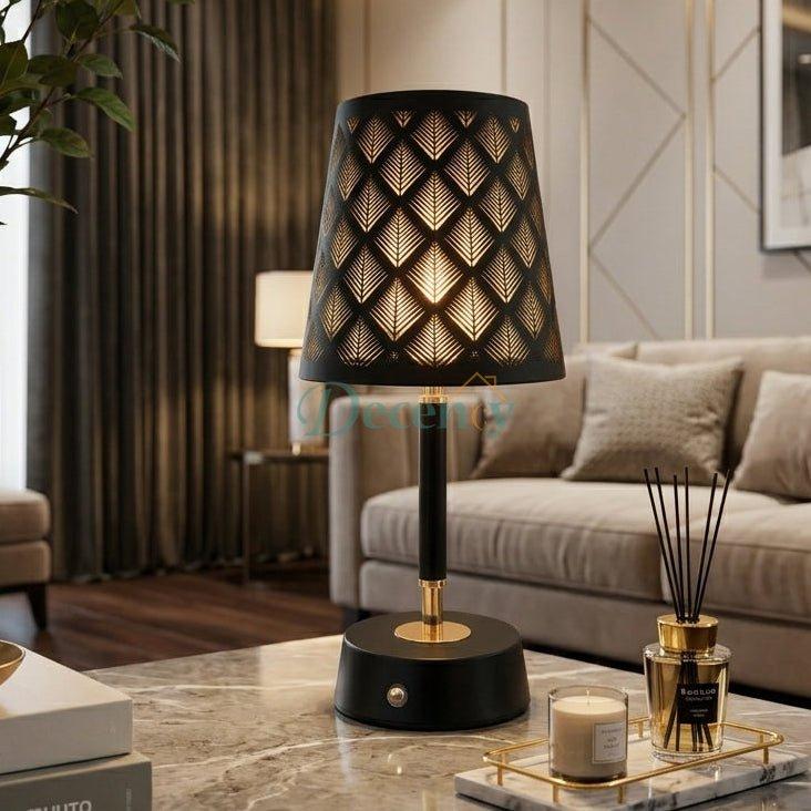 Black and gold metal table lamp with geometric leaf cutout shade on marble table