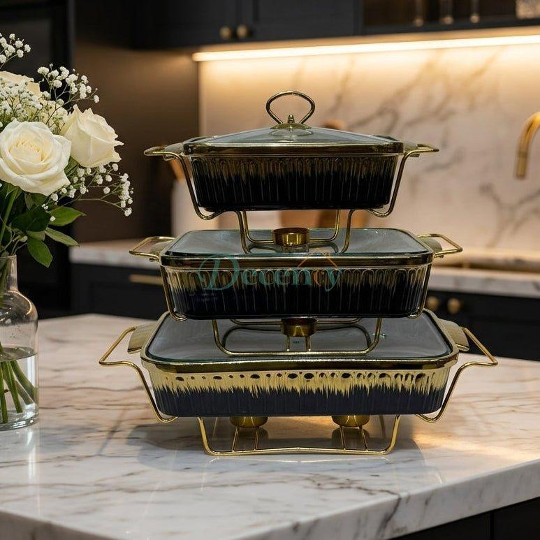 Stacked 3-piece luxury ceramic chafing dish set in black and gold with glass lids on a marble countertop.