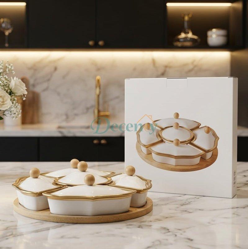 White ceramic dry fruit serving tray set with gold rims and bamboo platter on a marble kitchen counter