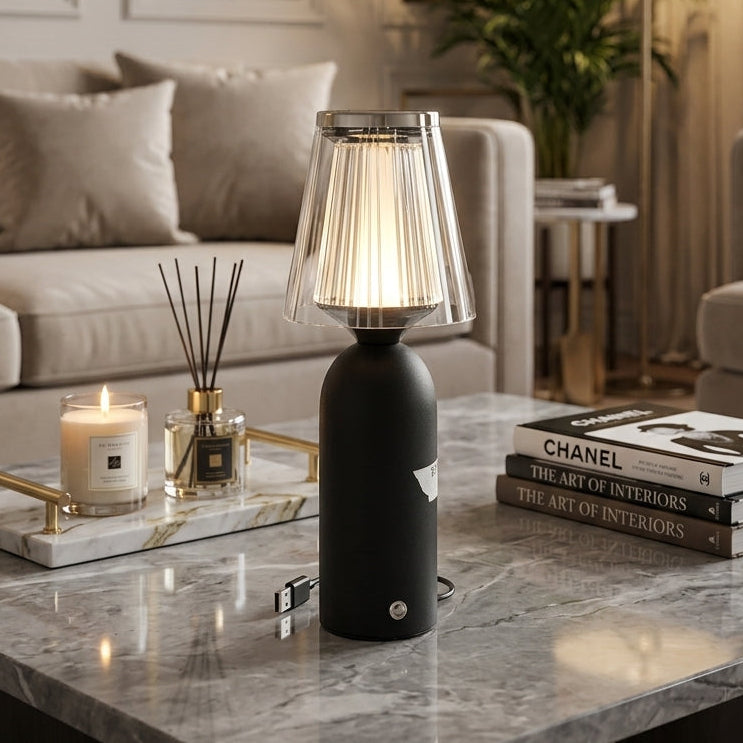 Modern black cordless table lamp with a fluted crystal shade placed on a marble coffee table in a modern living room.