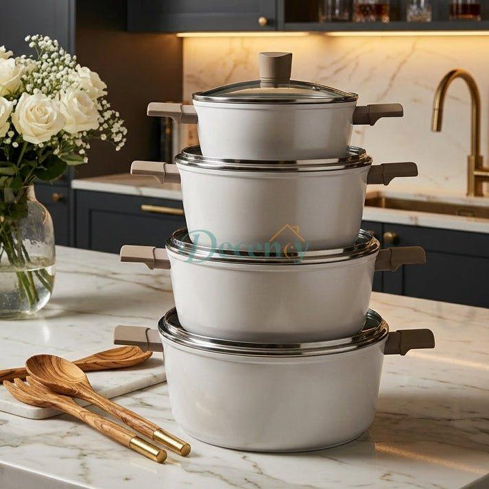 Stacked 4-piece white OSFE non-stick casserole pots with glass lids on marble countertop