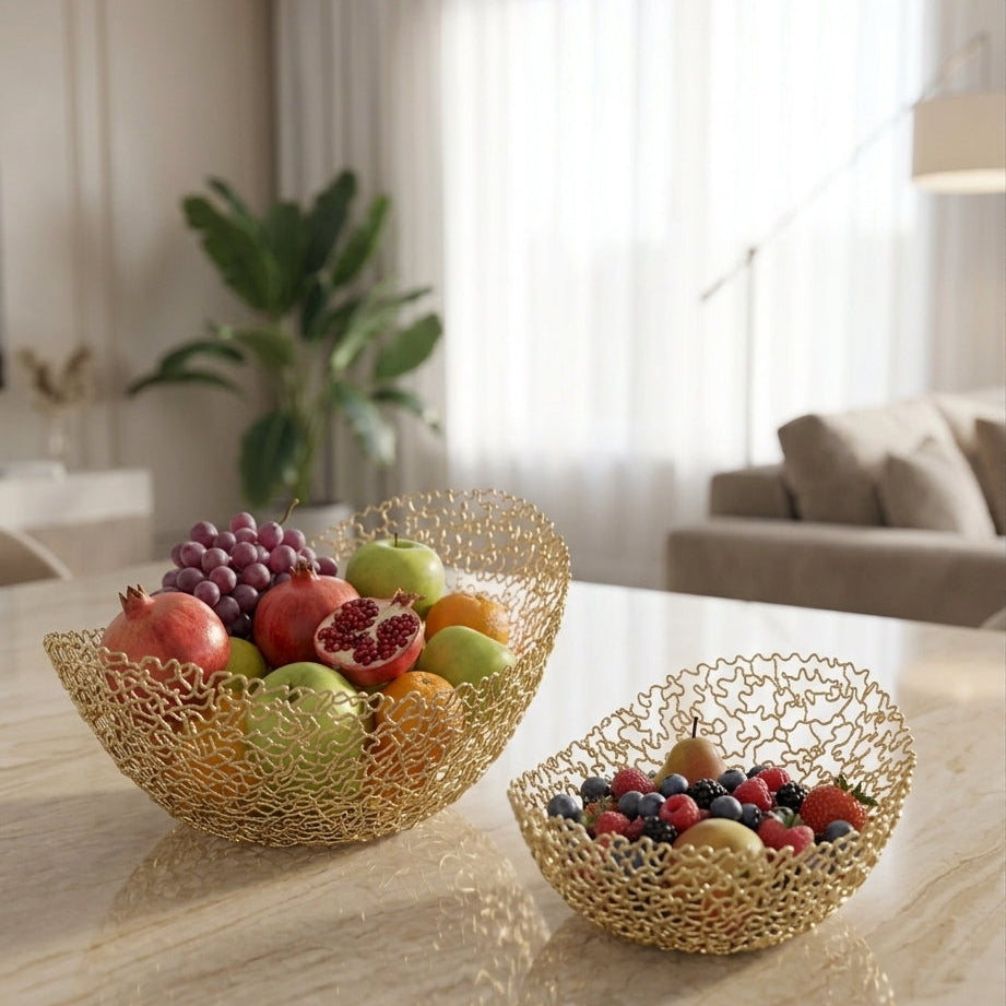 Set of two oval gold wire mesh fruit baskets filled with fresh fruits on a marble dining table.