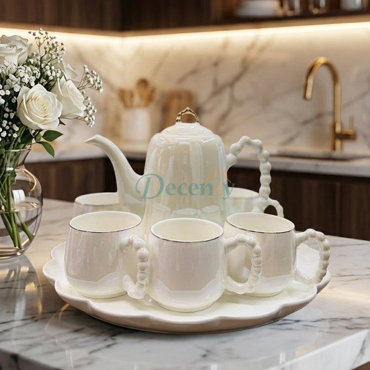 8-piece revolving ceramic tea set with pearl handle cups arranged on a marble table.
