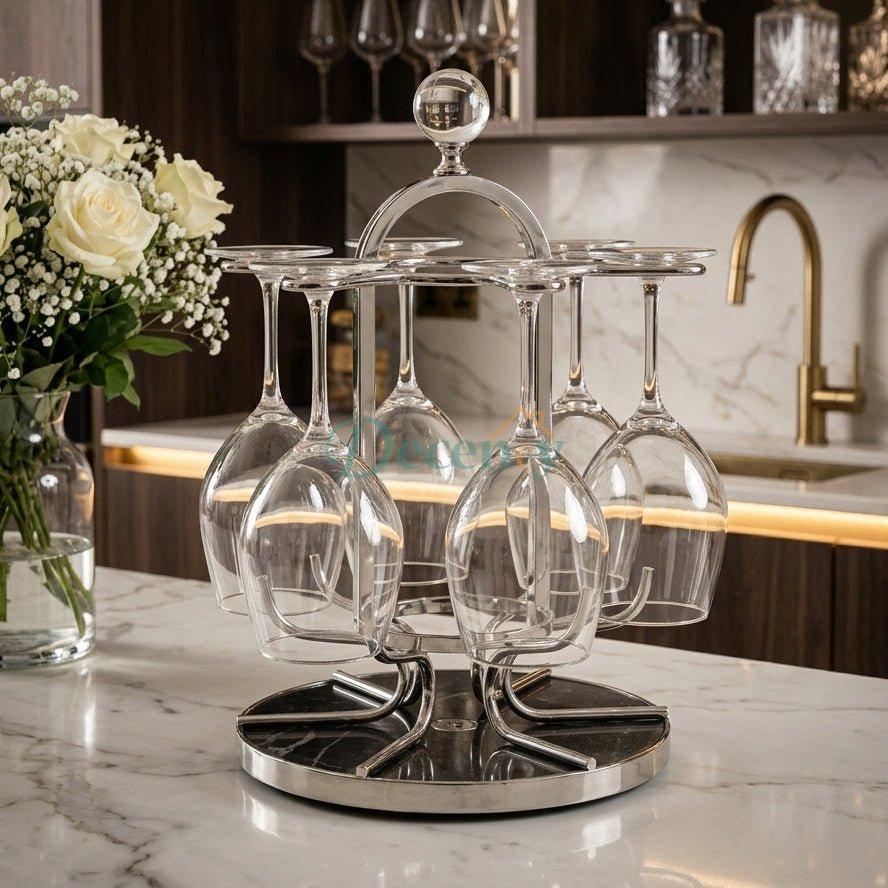 Front view of a chrome revolving glass holder rack on a marble base holding upside-down stemmed glasses