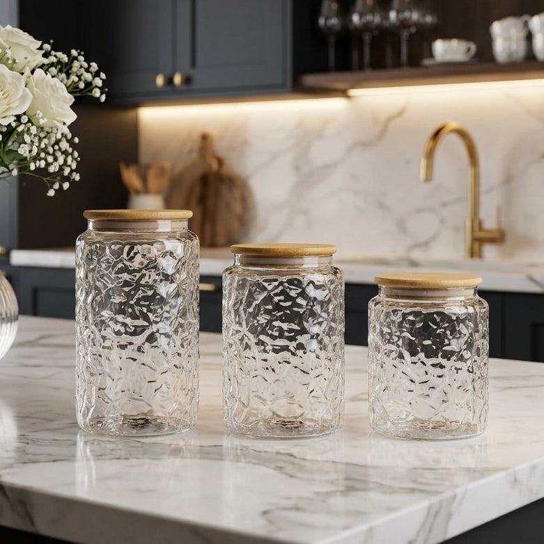 3-piece textured glass storage jar set with wooden lids displayed on a marble kitchen island