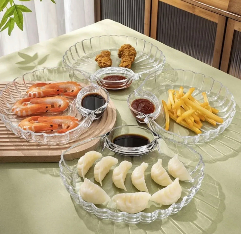 2-piece set of clear glass shell-shaped serving plates displayed on a dining table with snacks