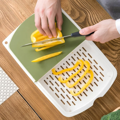 Hands slicing a yellow bell pepper on a green 3-in-1 cutting board next to a white built-in strainer tray