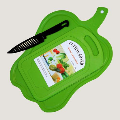 A bright green plastic cutting board with a matching lid, shown on a light gray background. A black-handled knife with a slotted blade rests diagonally across the board, and a product label is visible on top of the board.