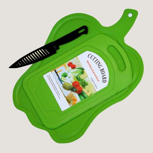 A bright green plastic cutting board with a matching lid, shown on a light gray background. A black-handled knife with a slotted blade rests diagonally across the board, and a product label is visible on top of the board.