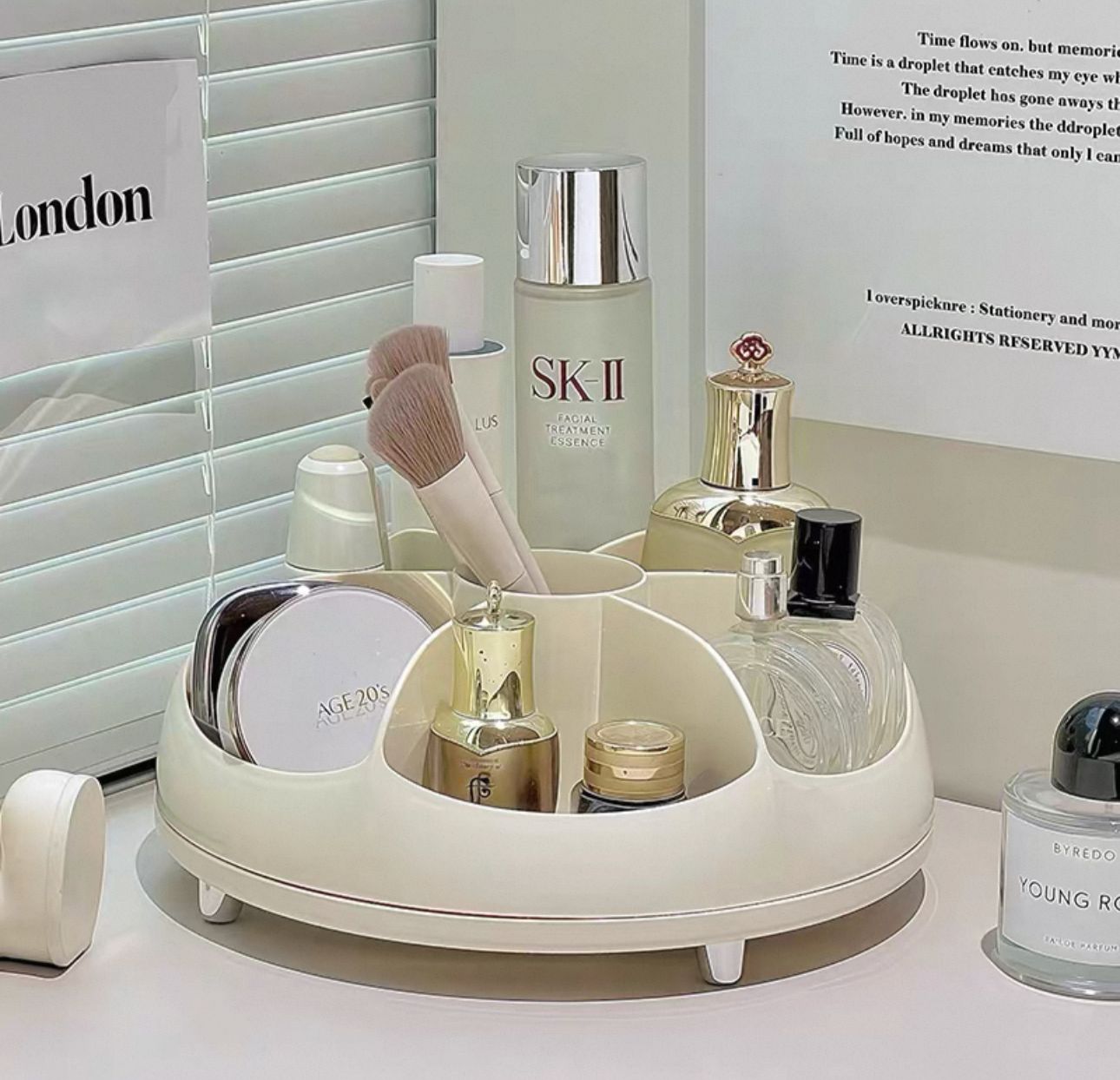 Off-white 360 rotating makeup organizer tray filled with cosmetics and skincare bottles on a vanity table.