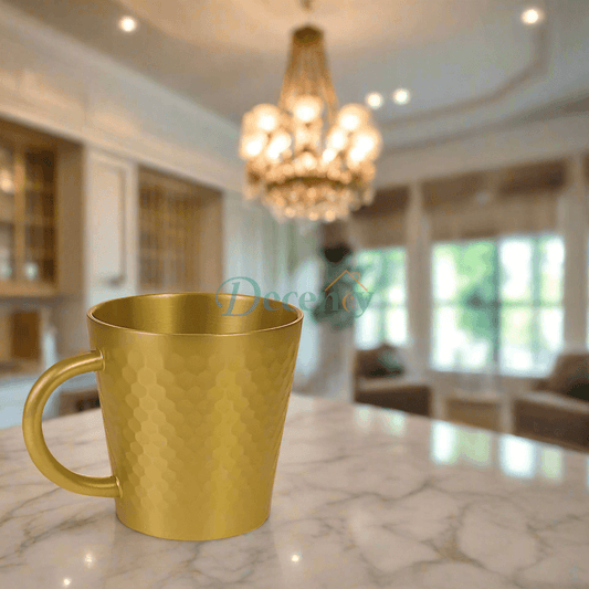 Gold mug on a marble countertop in a kitchen with a chandelier.

