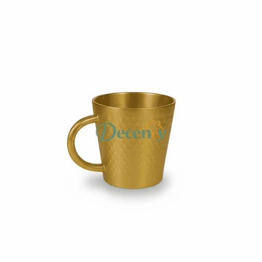 Gold mug on a marble surface with a blurred background of a room with a chandelier.

