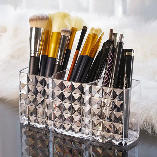 Clear acrylic 3-slot makeup brush organizer filled with cosmetic brushes on a vanity counter