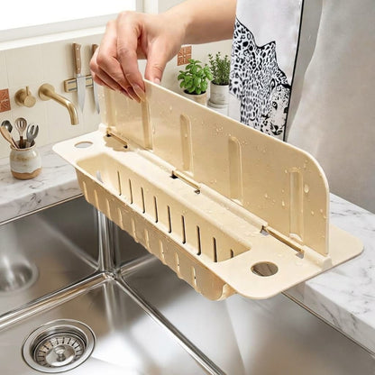 Adjustable beige kitchen sink drain rack placed over a stainless steel sink counter