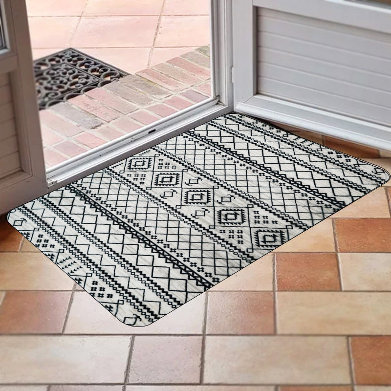 Bare feet standing on a cushioned anti-fatigue memory foam kitchen rug with a black and white geometric pattern. 