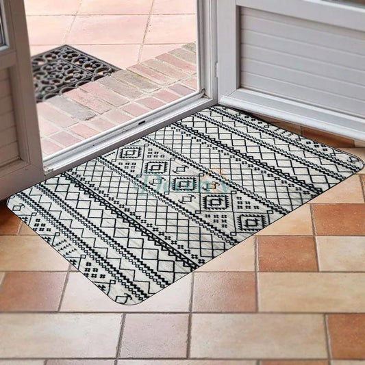 Bare feet standing on a cushioned anti-fatigue memory foam kitchen rug with a black and white geometric pattern. 