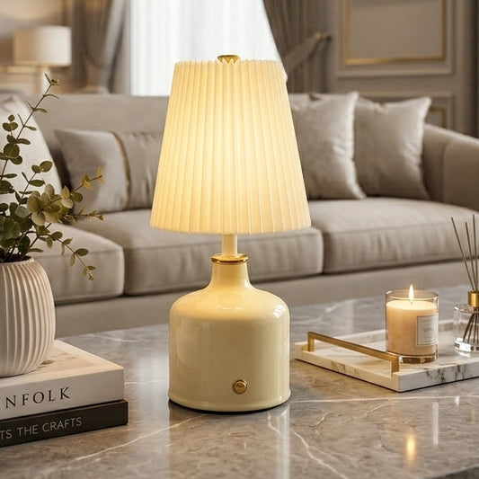 Illuminated cream Aurora pleated ceramic table lamp on a marble coffee table