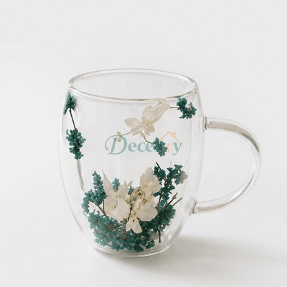 Azure Blossom double-wall glass mug with real blue and white dried flowers on a woven coaster.
