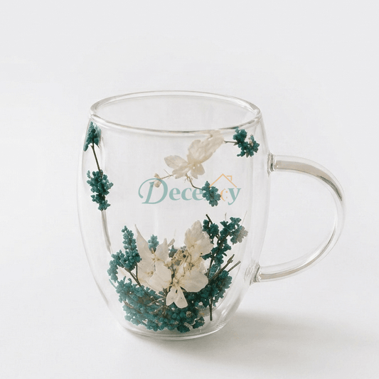 Azure Blossom double-wall glass mug with real blue and white dried flowers on a woven coaster.