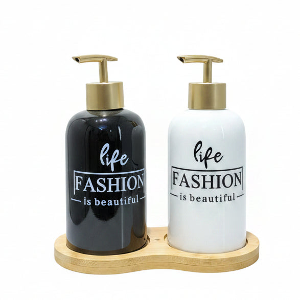 Black and white ceramic liquid soap dispenser set with gold pumps on a bamboo tray