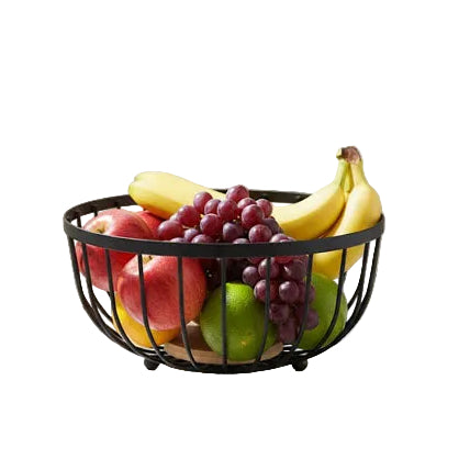Black wire fruit basket filled with fresh apples, bananas, and grapes on a marble countertop