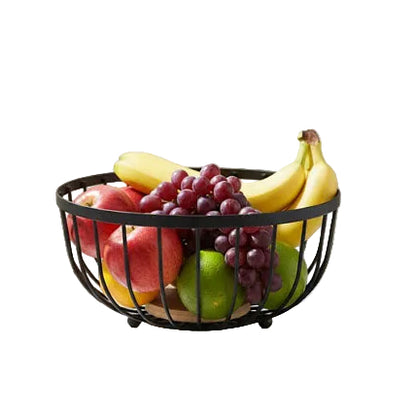Black wire fruit basket filled with fresh apples, bananas, and grapes on a marble countertop