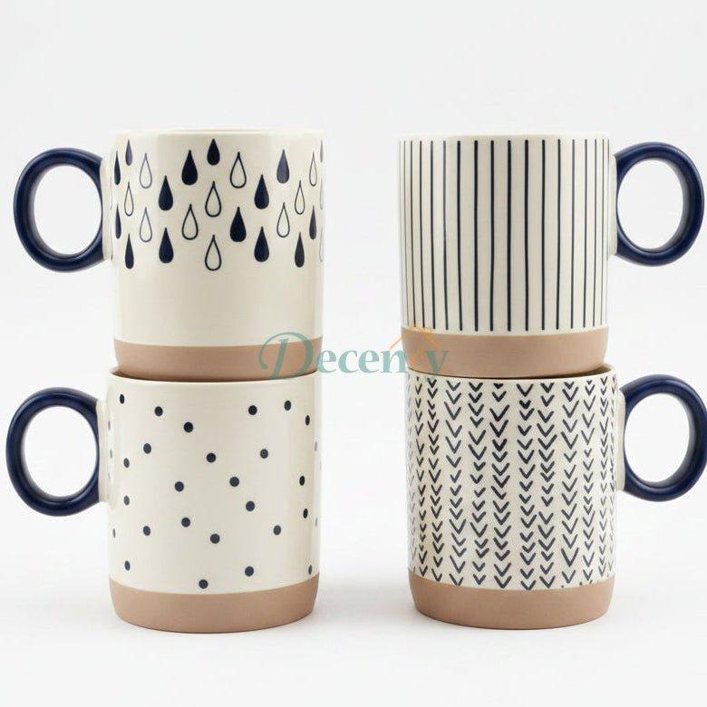 Set of 4 ceramic coffee mugs with geometric prints displayed on a kitchen marble countertop.