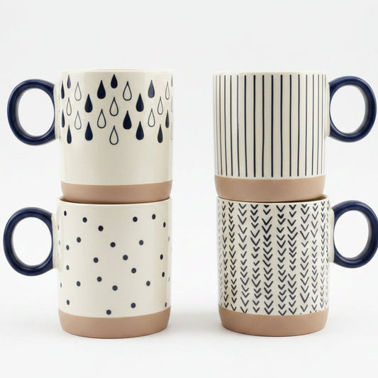 Set of 4 ceramic coffee mugs with geometric prints displayed on a kitchen marble countertop.