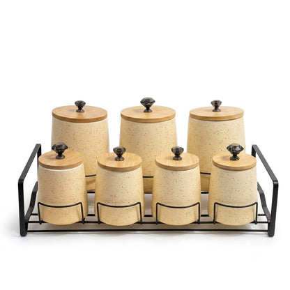 Three ceramic kitchen storage jars featuring polka dots and stripes arranged on a wooden tray.