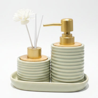 White ribbed ceramic soap dispenser and reed diffuser with flower sticks sitting on a ceramic tray.