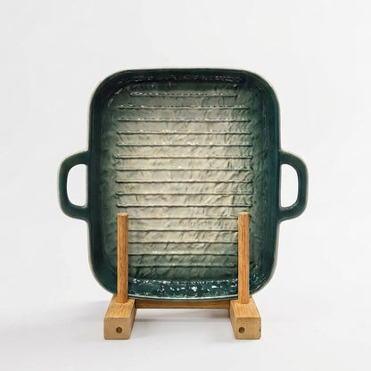 Green ceramic rectangular grill pan resting on a wooden display stand.   