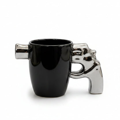 Premium ceramic revolver mug with a shiny metallic pistol grip handle on a white marble surface.