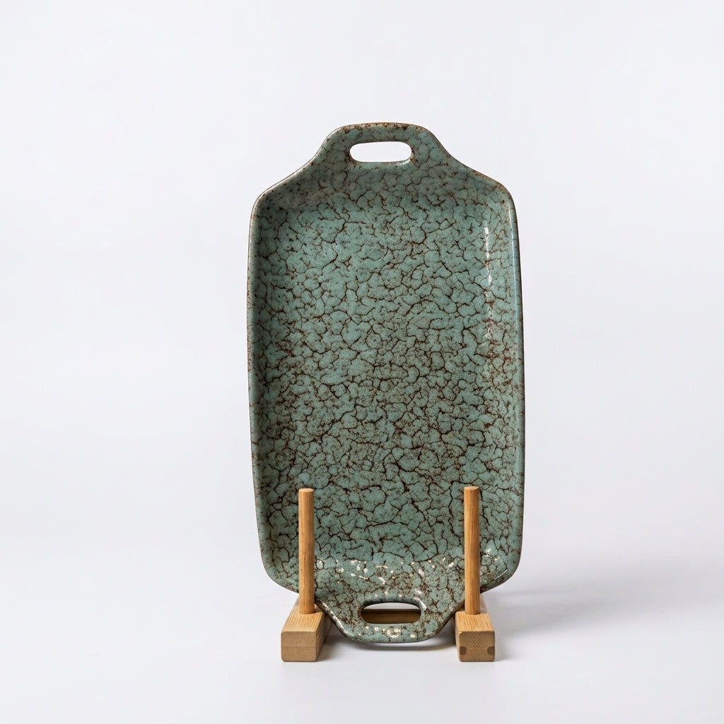 Turquoise crackle glazed ceramic serving tray standing upright on a wooden display holder. 
