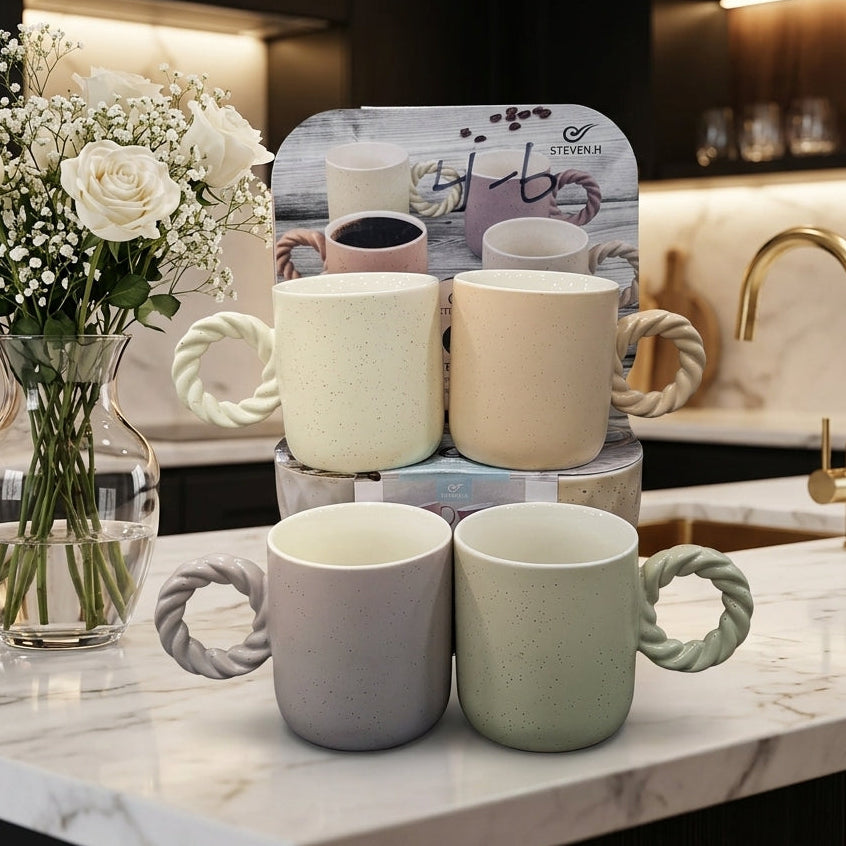 Set of 4 pastel ceramic coffee mugs with twisted handles on a kitchen marble counter.