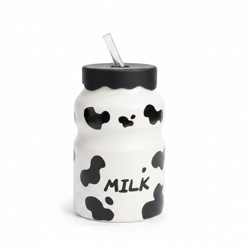 Front view of white cow print glass milk bottle with black lid and glass str