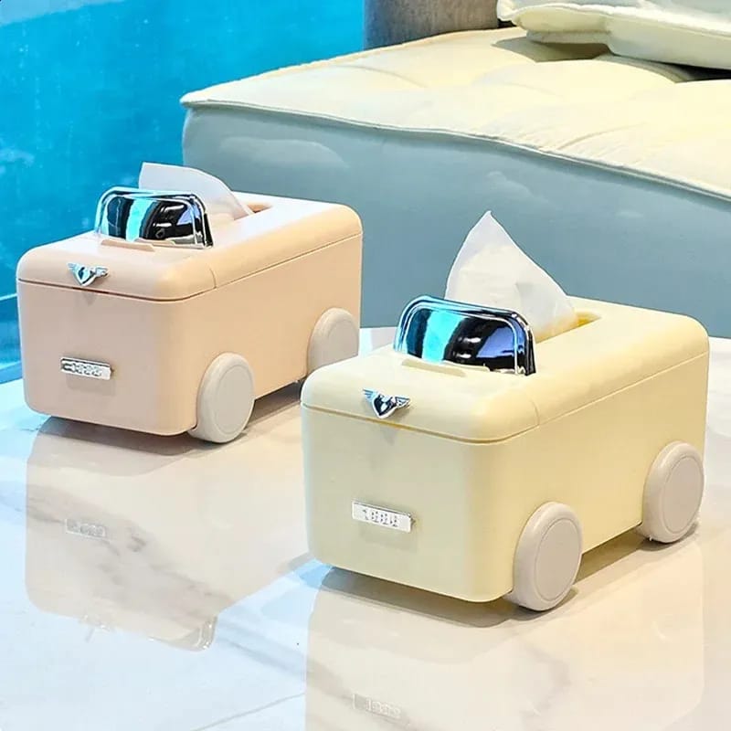 Pair of cute pastel car-shaped tissue box dispensers in cream and soft pink on a table.