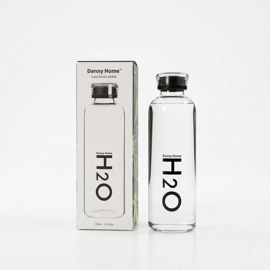 Danny Home 750ml clear glass water bottle with black H2O print next to its original box on a marble countertop.