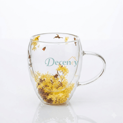 Double wall glass coffee mug filled with real dried yellow flowers on a wooden table.