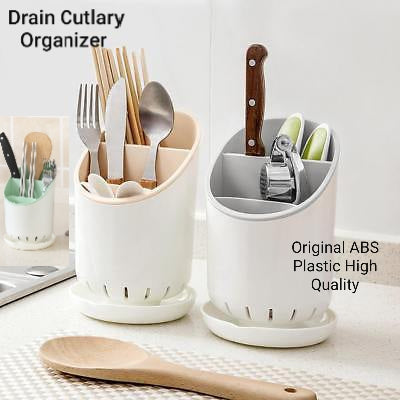 White plastic drain cutlery organizer stand holding spoons, forks, and knives on kitchen counter.