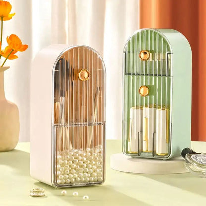 White and sage green dustproof makeup brush organizer boxes with ribbed acrylic doors on a dressing table.