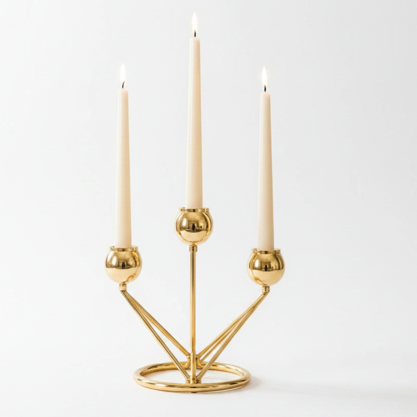 Elegant gold metal candelabra holding three white taper candles on a polished table surface