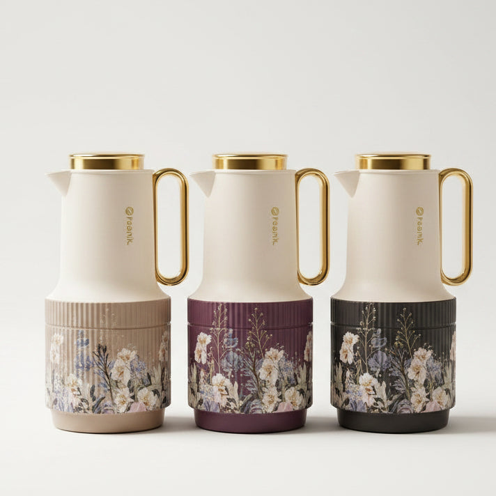 Three luxury Feenik 1 Litre vacuum flasks in beige, purple, and black with floral bases on a marble kitchen counter.