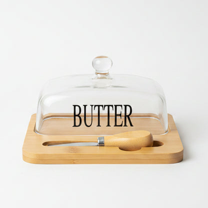 Clear glass butter dish printed with BUTTER text on wooden tray with spreader knife