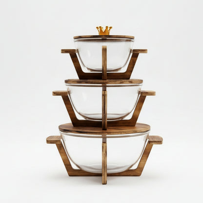 Set of 3 separate clear glass serving bowls stacked with individual wooden stands on a kitchen island