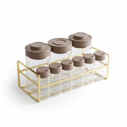 clear glass spice jar set with brown airtight caps in a gold metal rack on a marble countertop
