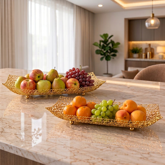 Gold boat-shaped wire fruit basket filled with fresh apples and grapes on a marble kitchen counter