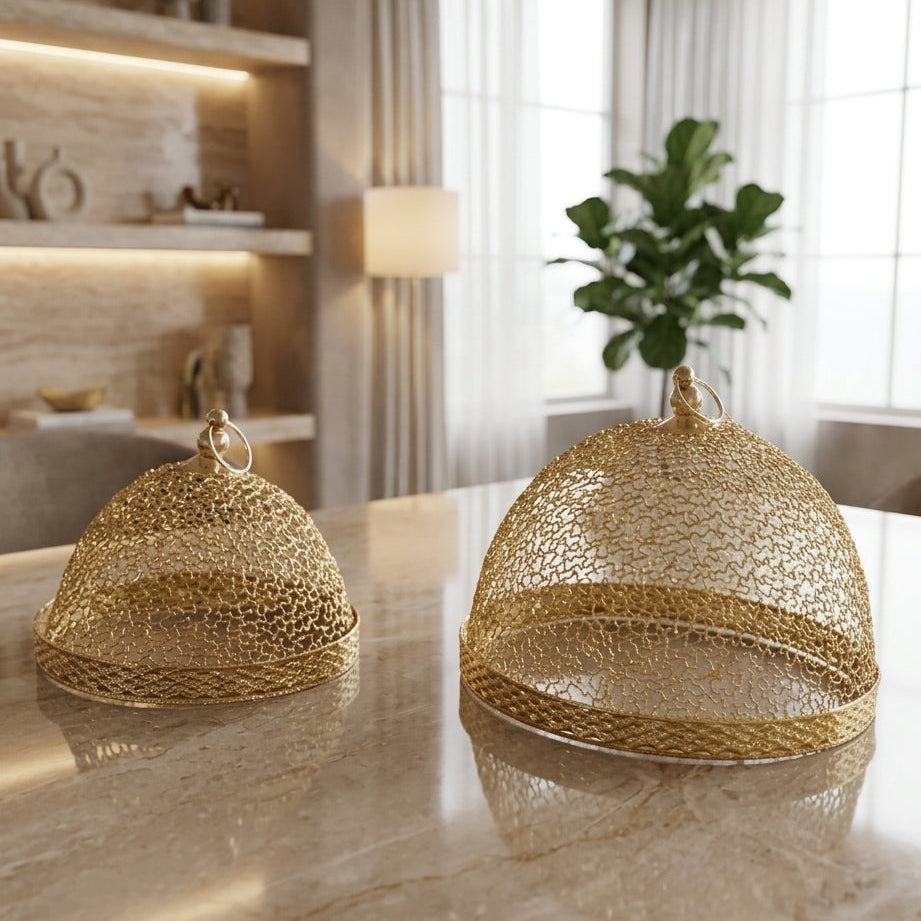 Pair of elegant gold wire mesh food covers sitting on a marble dining table